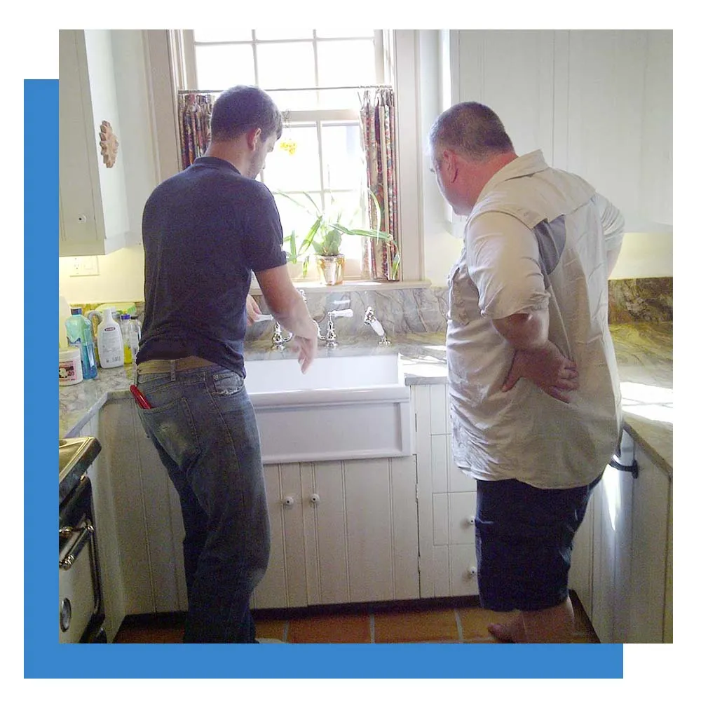Showing a customer the repair work done to a kitchen sink.