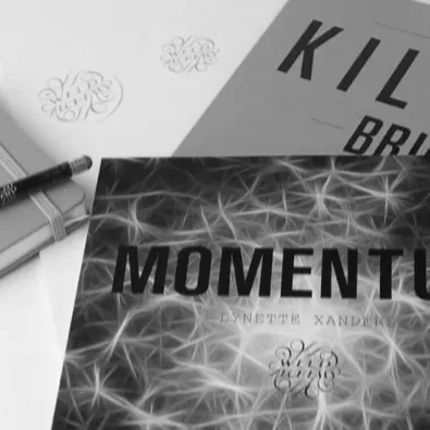 Angled close-up shot of a printed document titled 'KILLER BRIEF', showing the subtitle 'A better way to get creative work done', layered over another document, with a pale teal square border placed behind the photo