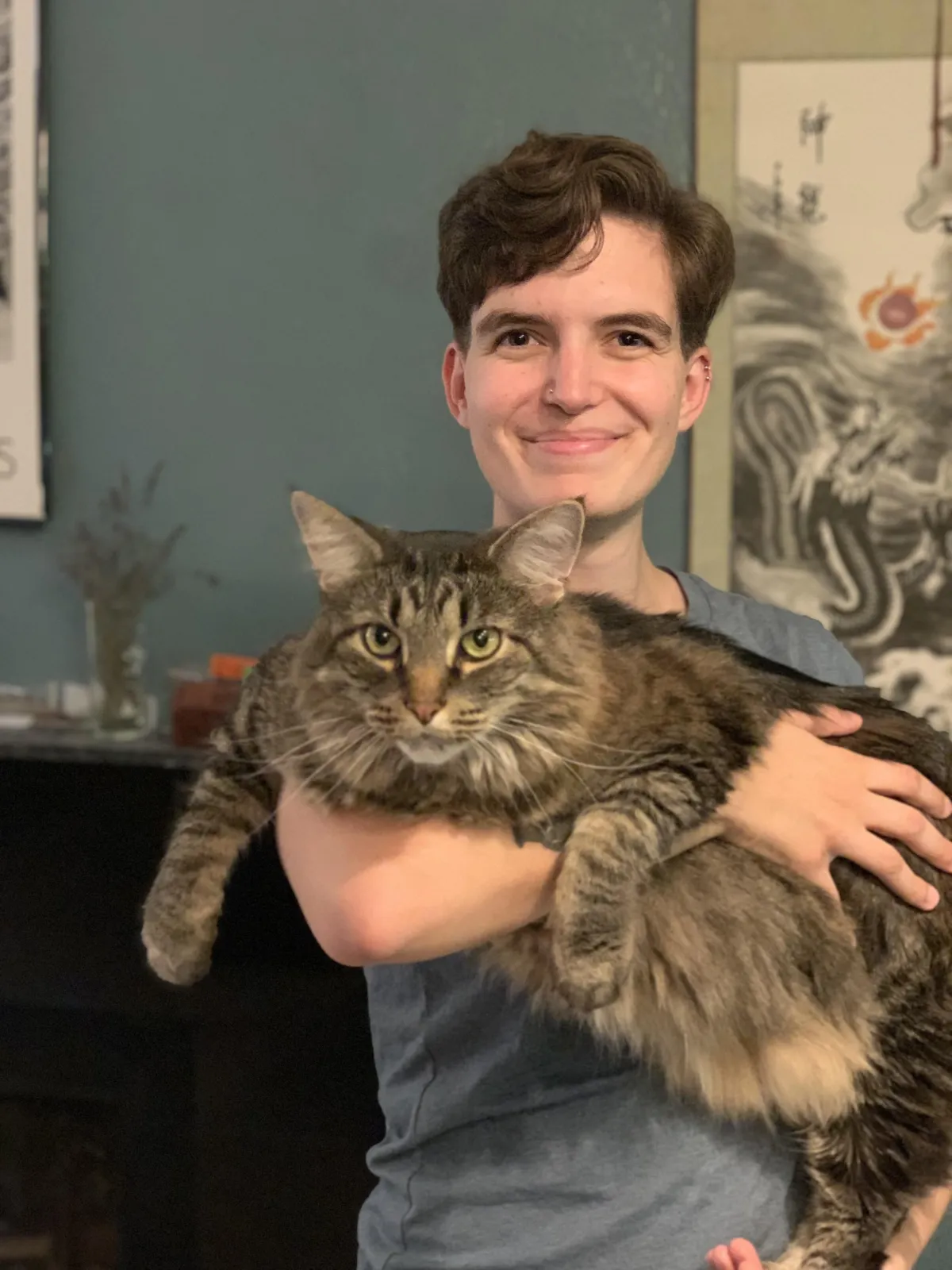 Sam holding a large, brown tabby wo is looking softly at the camera