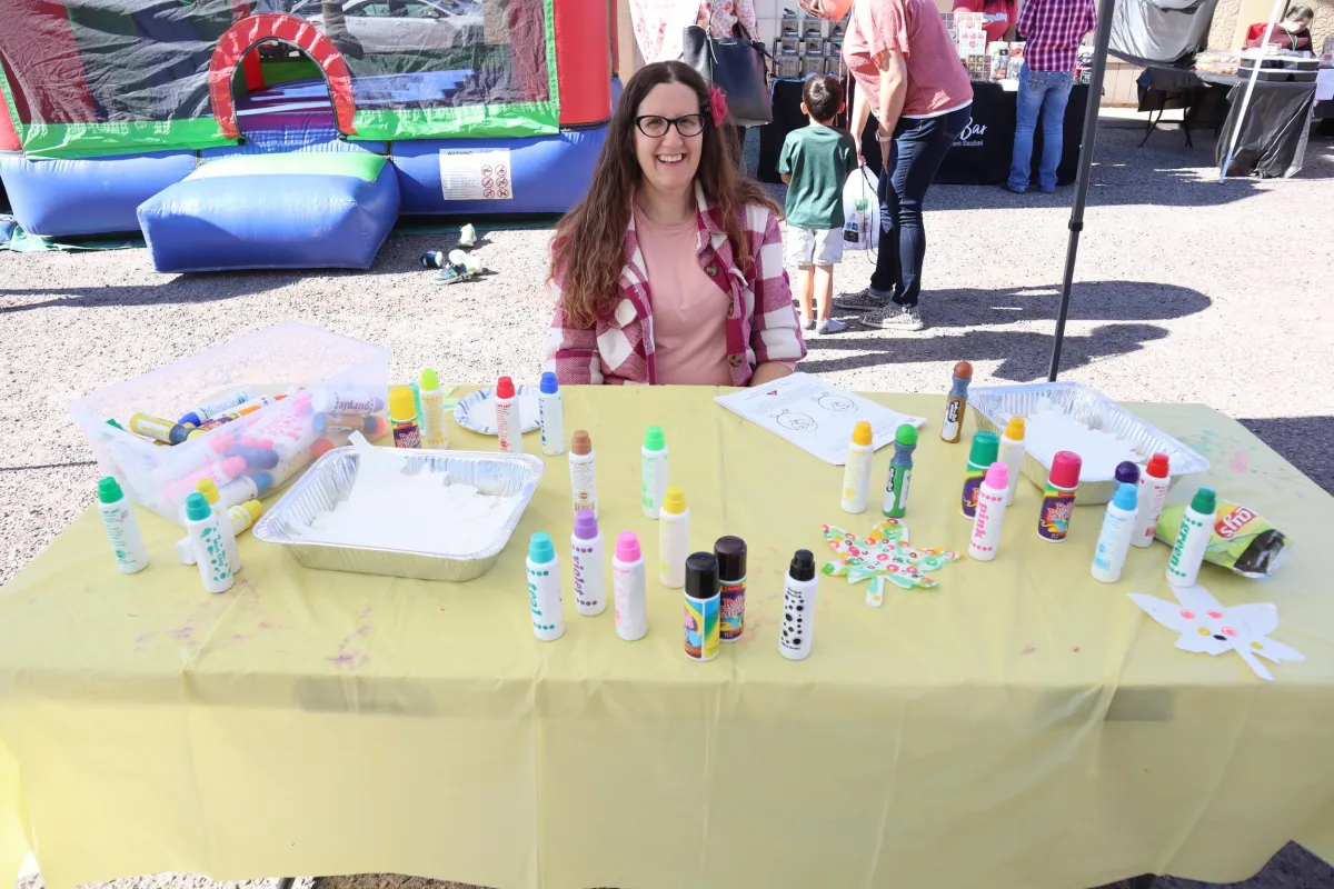 Local organizer hanging paper lanterns and fall bunting in a community hall, preparing cozy autumn decorations.