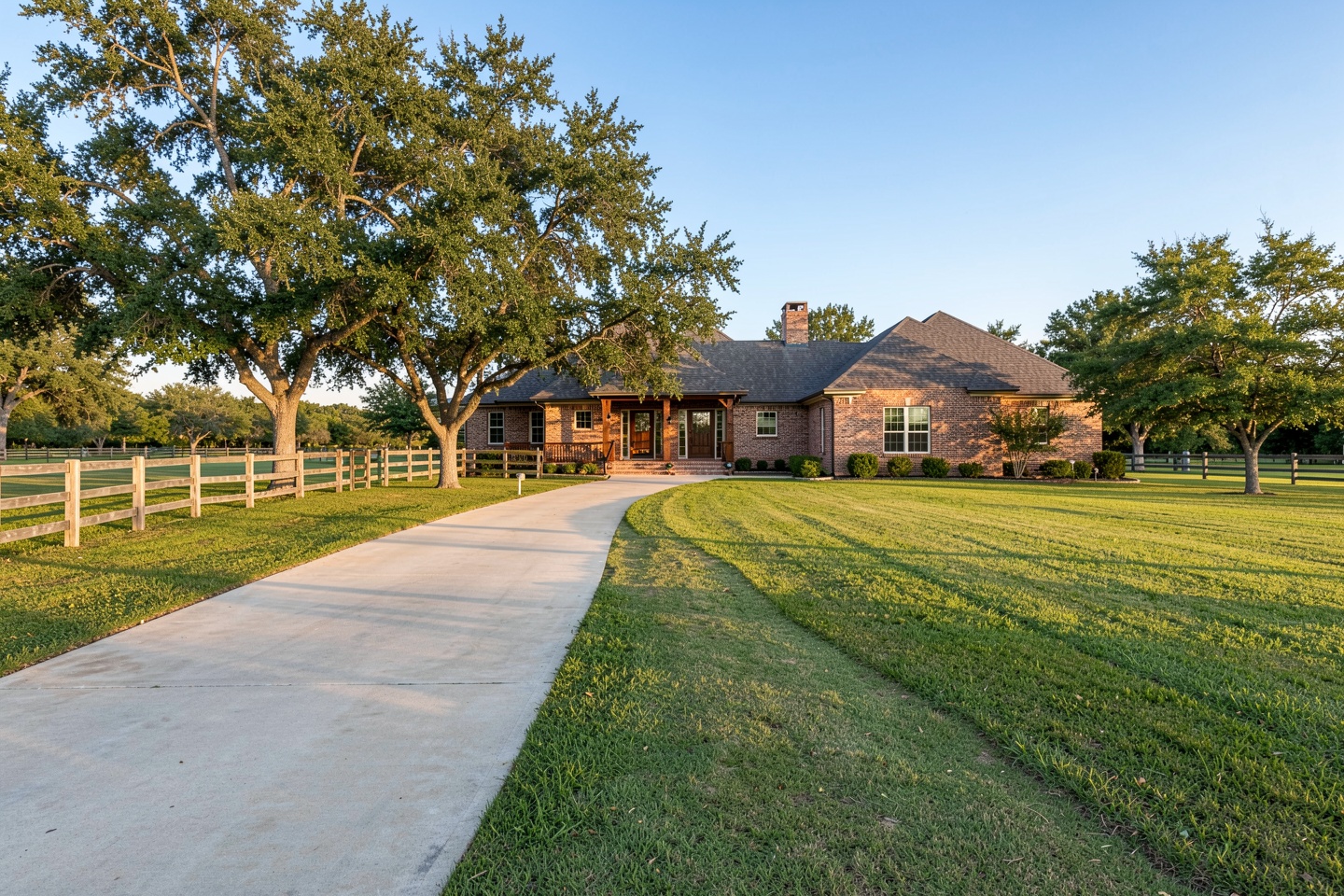 Custom brick home on acreage in Lucas, TX with a long driveway and board fence