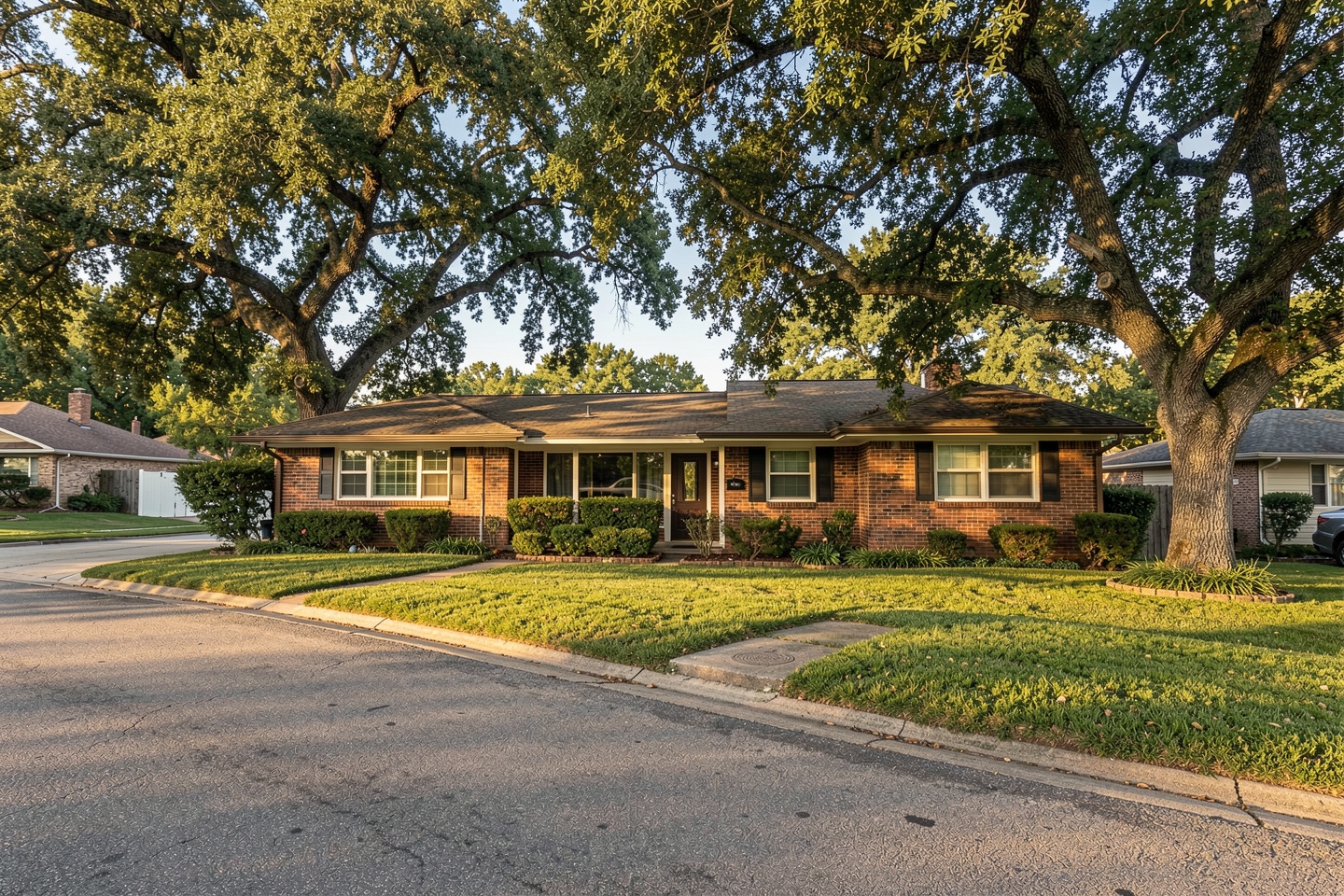 Single-story 1980s ranch-style brick home under mature shade trees in Plano, TX