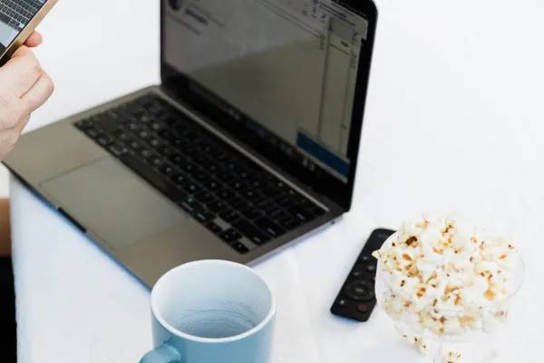 Laptop with blue mug and glass of popcorn