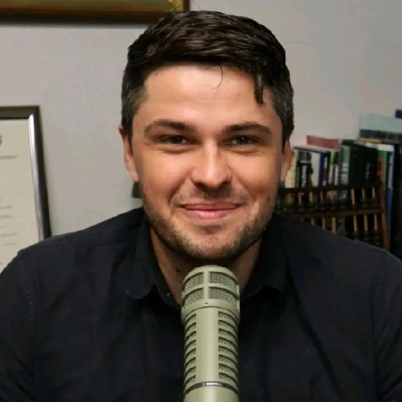 Ryan J Melton miling in front of a podcast microphone