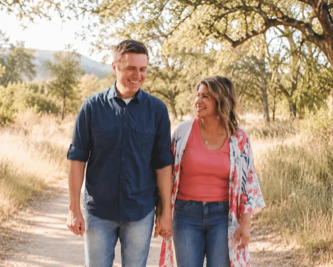 A casual portrait of a smiling man and woman outdoors in a natural setting.