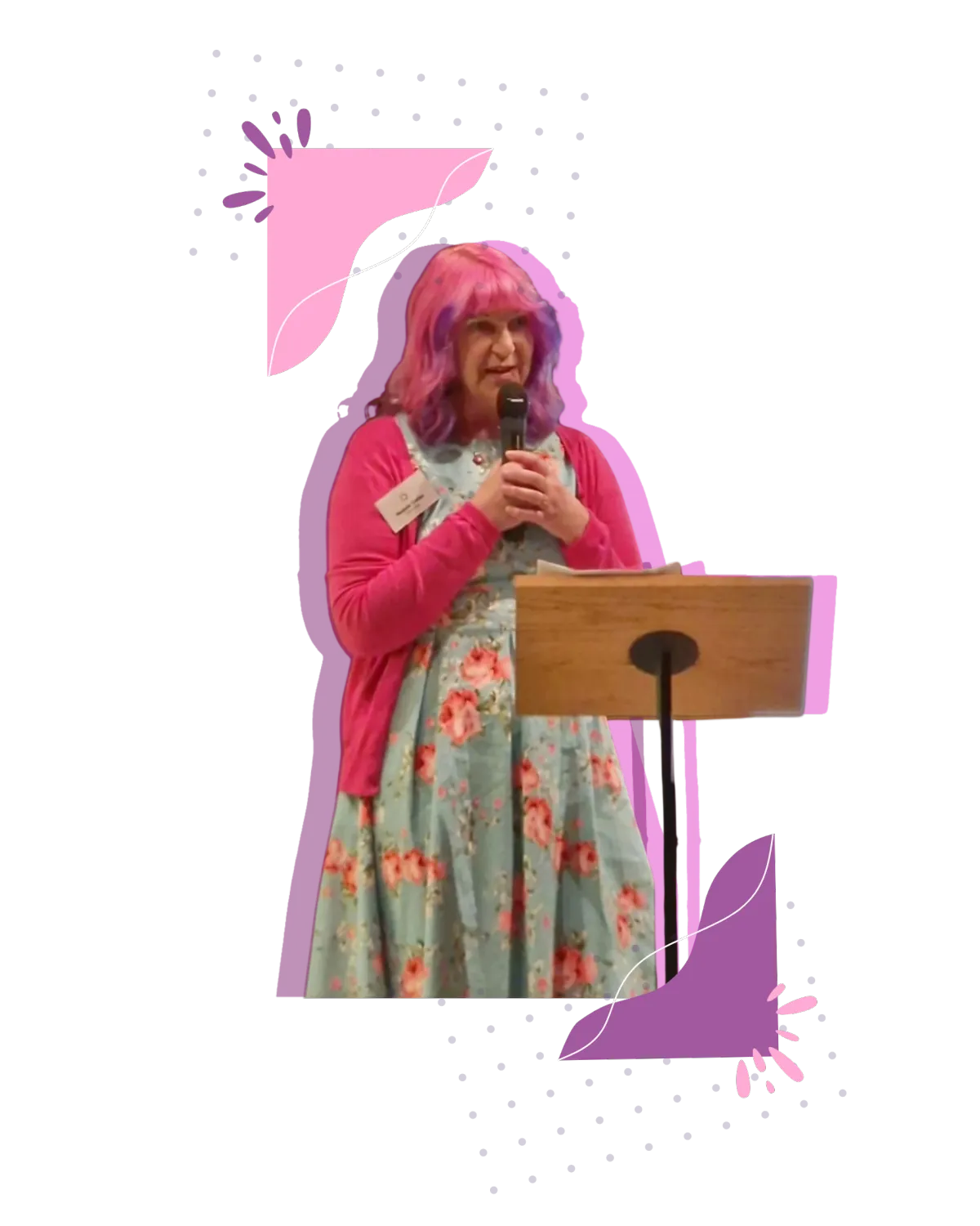 Melanie speaking on stage at School for Social Entrepreneurs. Holding a microphone, wearing a pink cardigan and has pink and purple hair.