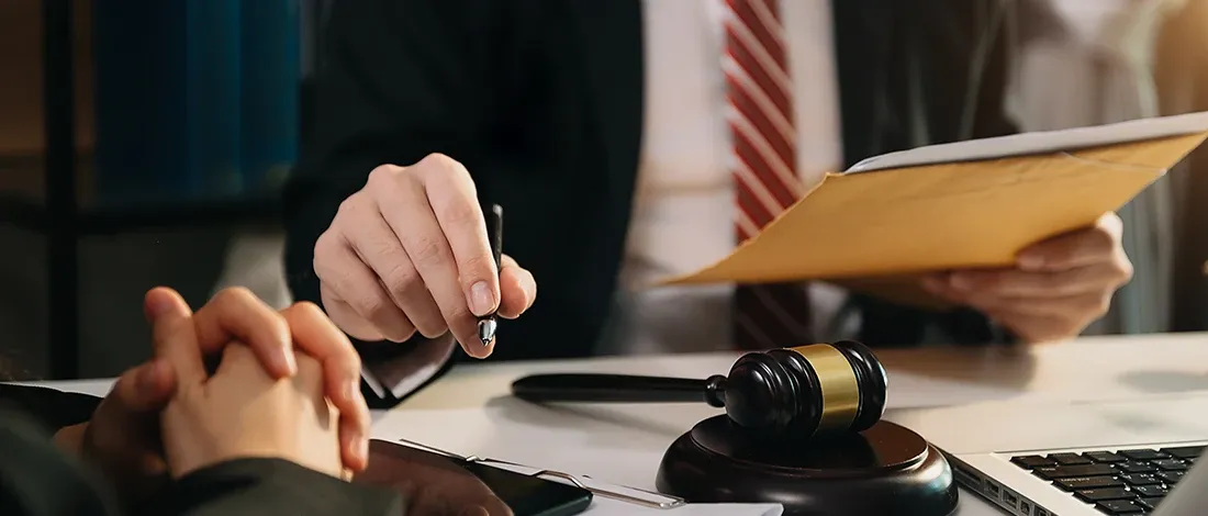 A business owner signing papers at a desk beside a gavel
