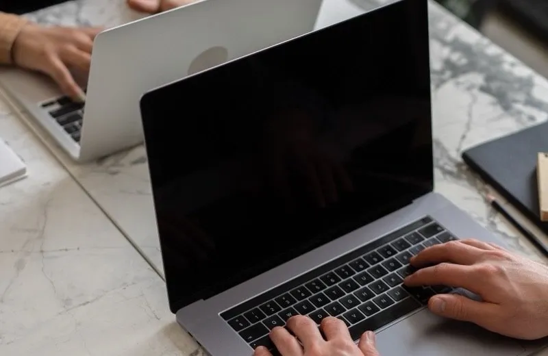 Two people working on laptops at a desk