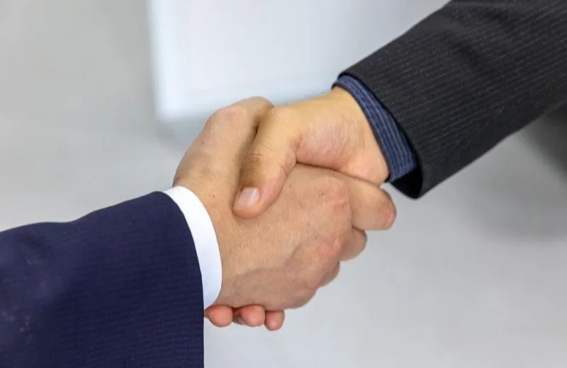 Two people shaking hands over a business agreement