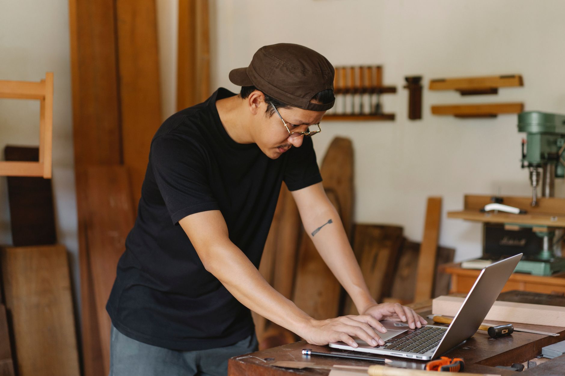 Concentrated ethnic man in casual clothes and eyeglasses browsing netbook while working in creative workspace in daytime