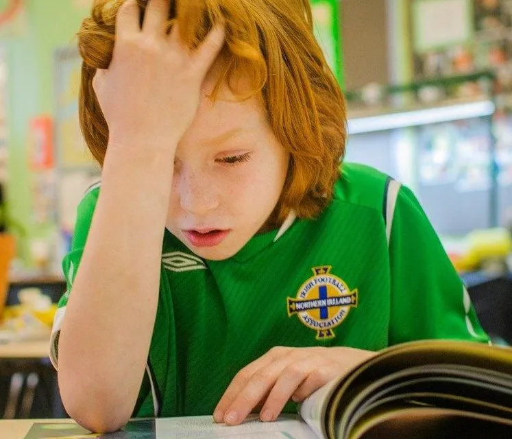 Child struggling to read while visually tracking lines of text