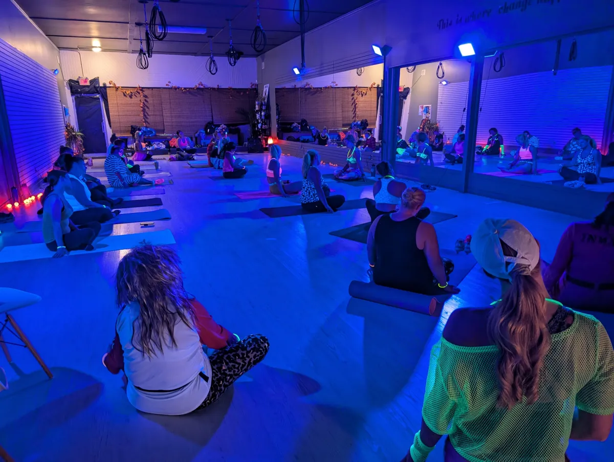 Friends dancing under neon glow lights at a fitness studio