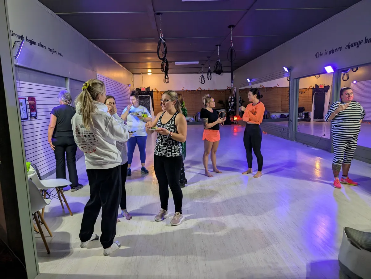 Group of friends laughing outside the studio in SKFitness hoodies, evening candid