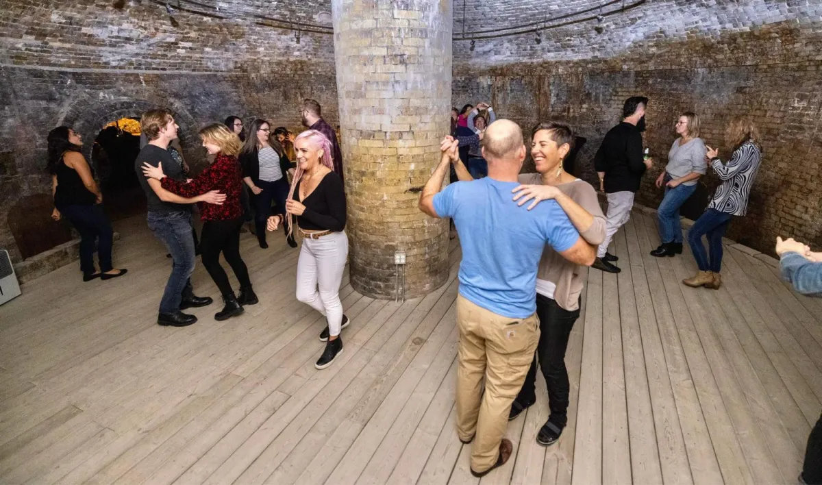 Group of friends laughing outside the studio in SKFitness hoodies, evening candid