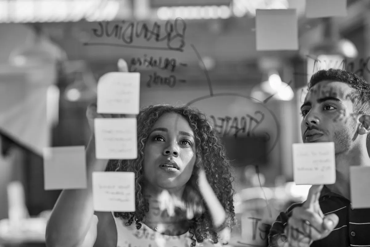 two person looking at clear white board.