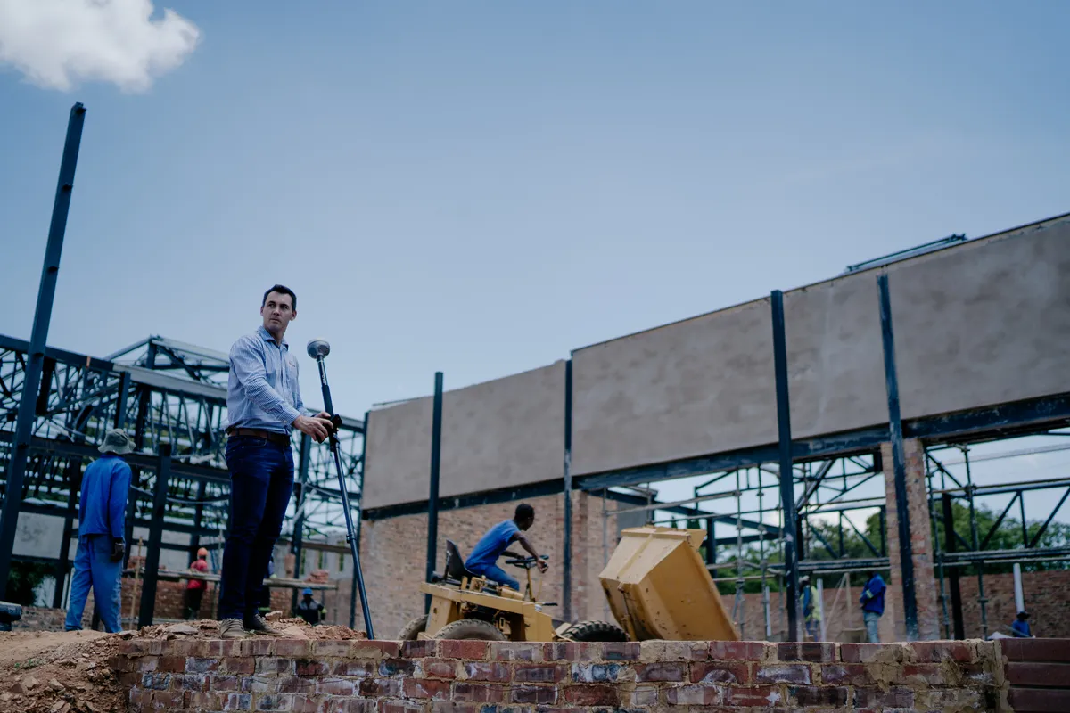 Surveyor operating modern total station instrumentation on site with high accuracy