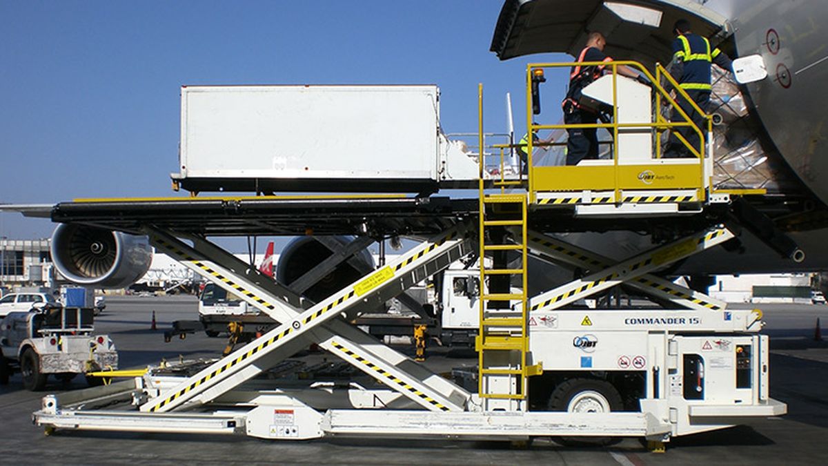 A high-loader raises a cargo container to the hold of a freighter aircraft — the belly-cargo and freighter options that move Ugandan produce by air.