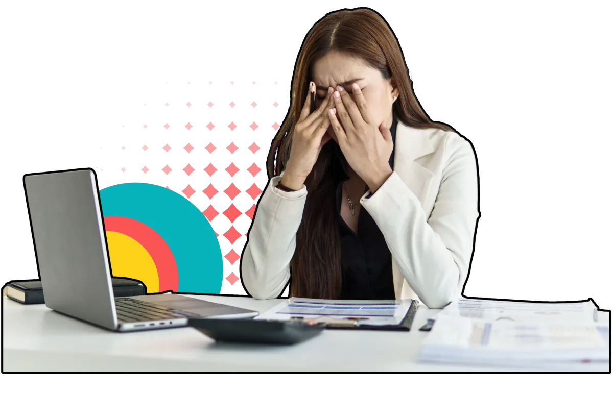 A woman in a white blazer sits at a desk, overwhelmed, with her hands covering her face. 
