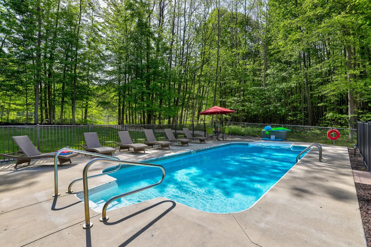 alt="Spacious inground pool with water slide at Holland, MI vacation rental, perfect for family fun and relaxation"