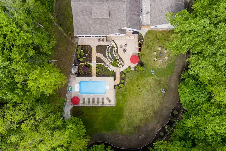alt="The Maple property in Holland, Michigan featuring a large pool with water slide and outdoor furniture"