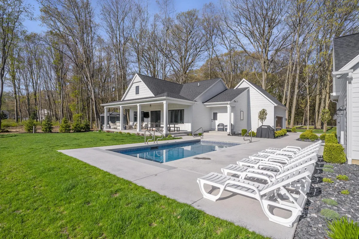 alt="Spacious inground pool with water slide at Holland, MI vacation rental, perfect for family fun and relaxation"