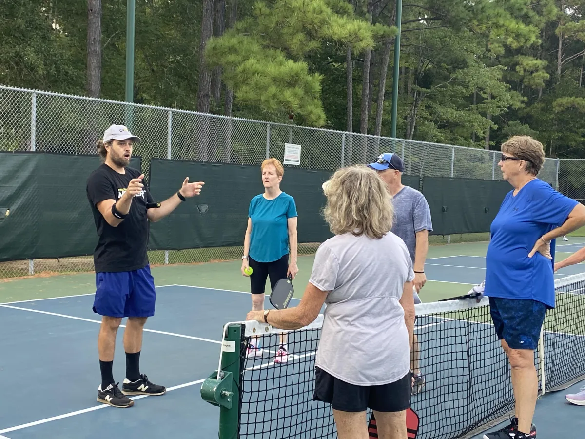 Adults playing pickleball in a group clinic with Coach Chris