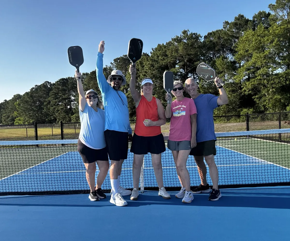 group photo of pickleball players celebrating on court