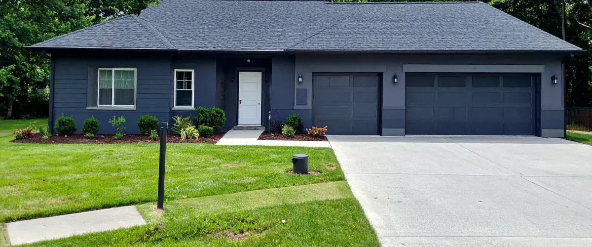 Modern gray house with clean driveway and trimmed lawn after pressure washing