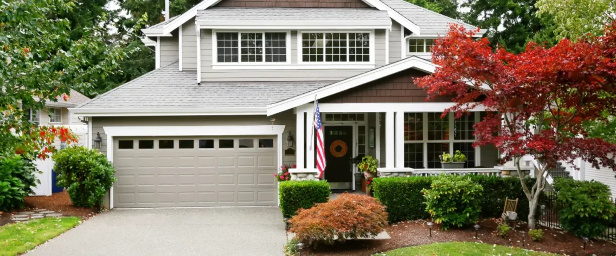 Suburban house with clean driveway, landscaped front yard, and American flag.
