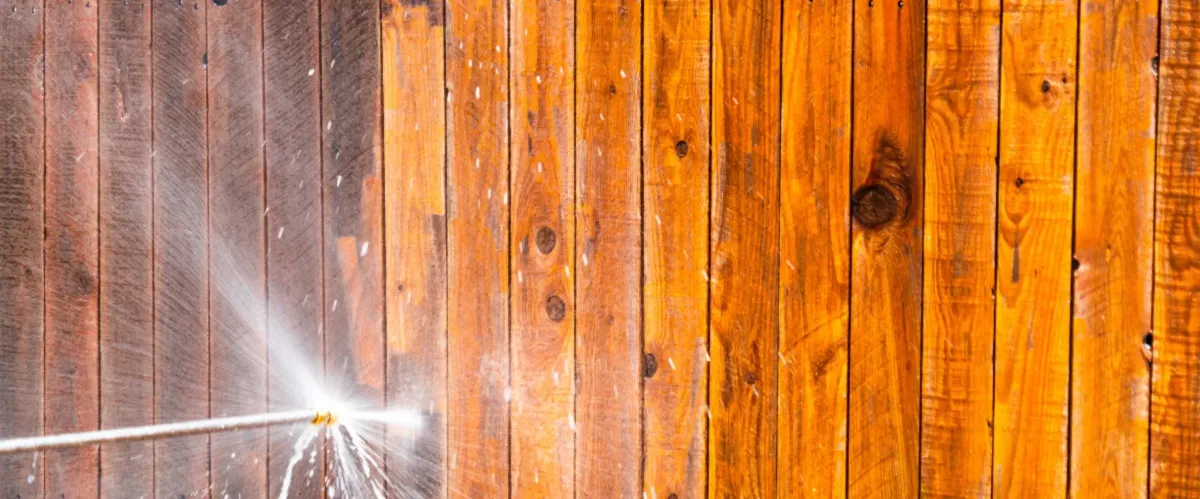 Pressure washer cleaning a wooden fence, showing dirt removal and wood restoration.