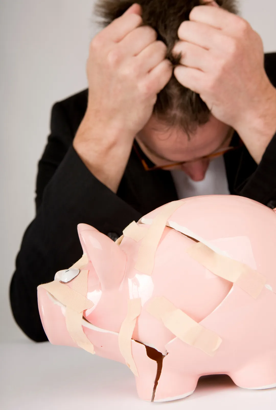 Hombre preocupado con una alcancía rota, simbolizando crisis financiera y necesidad de optimización de deudas
