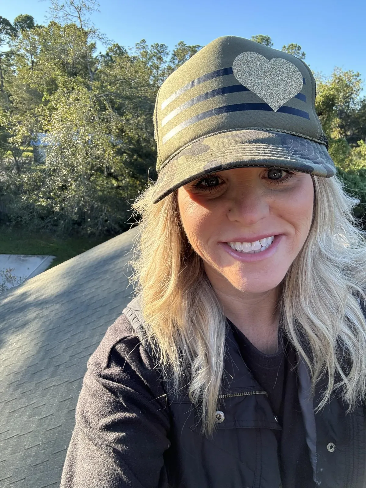  Kelly Brewin taking a selfie on a residential rooftop, wearing a purple polo and work boots during a roof inspection in Jacksonville FL