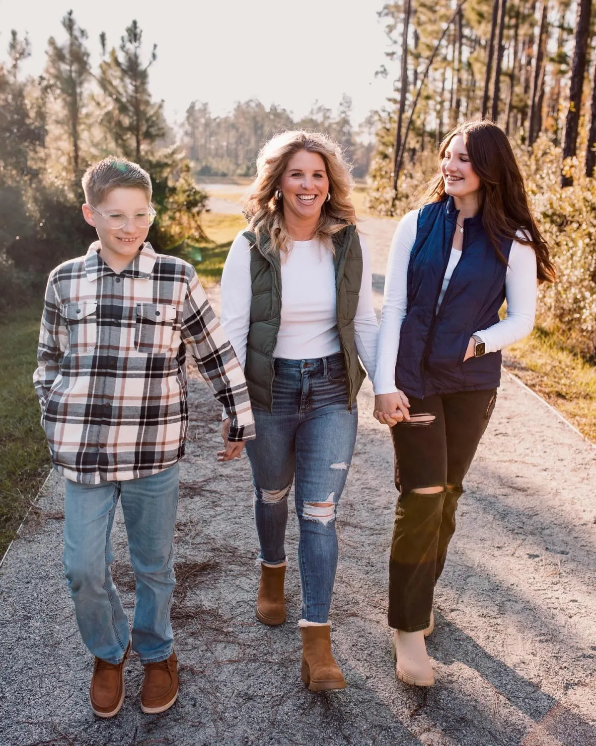 Kelly Brewin walking outdoors with her two kids on a tree-lined path, showing her personal story and family values