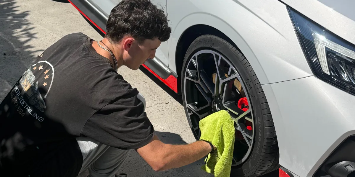 detailer cleaning rims on car