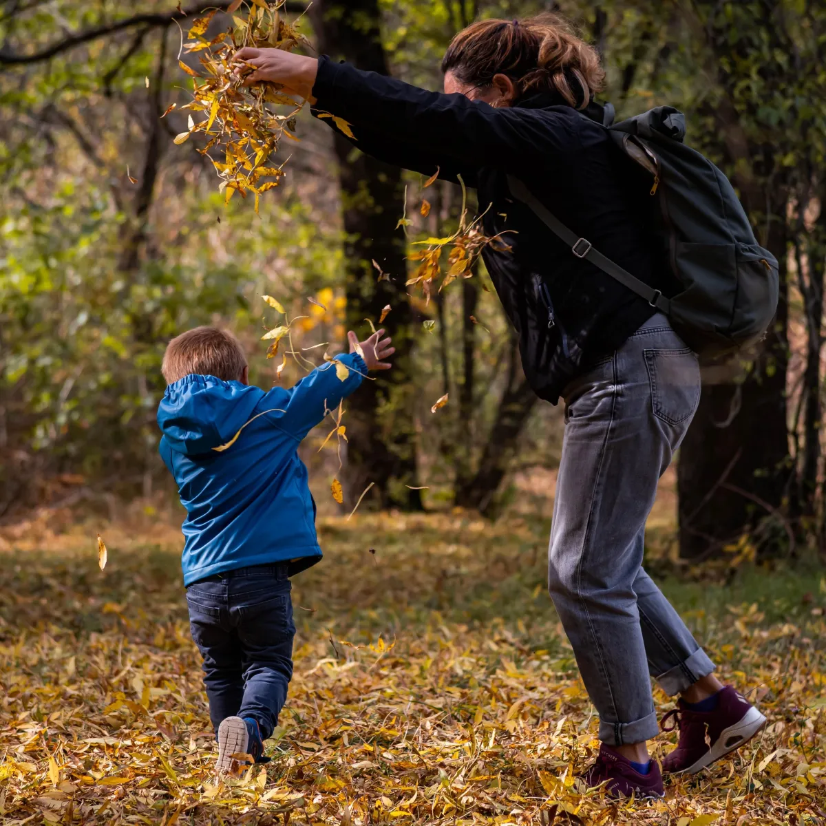 Image of a woman and child having fun in leaves