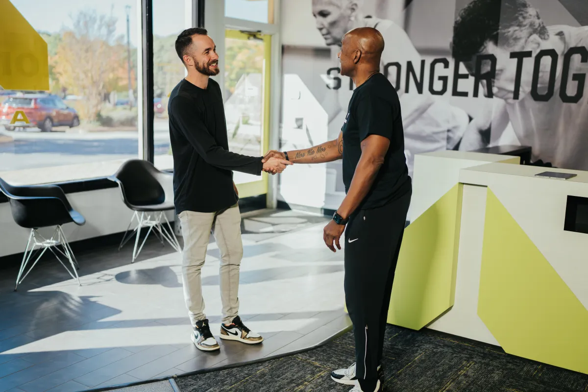 A personal trainer warmly welcoming a new comer into our supportive, judgment-free studio
