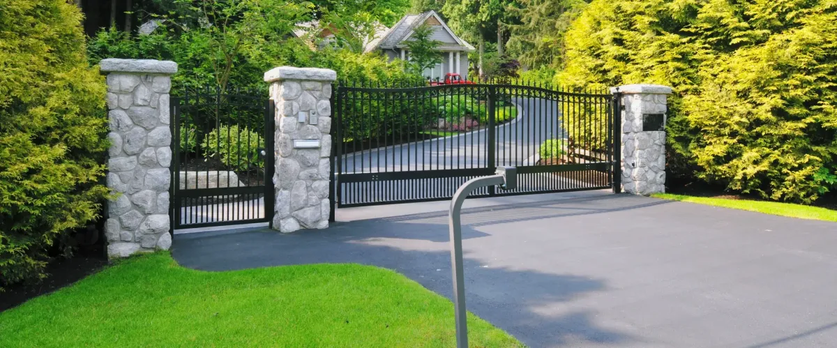Elegant gated driveway entrance to a luxury residential property with lush landscaping