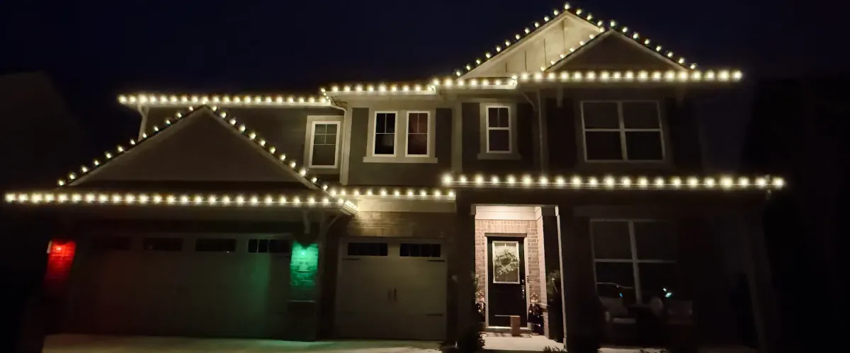  Two-story suburban home illuminated with permanent holiday lighting during nighttime