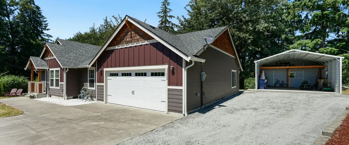 Modern home with attached garage and a detached shed, set in a wooded suburban area