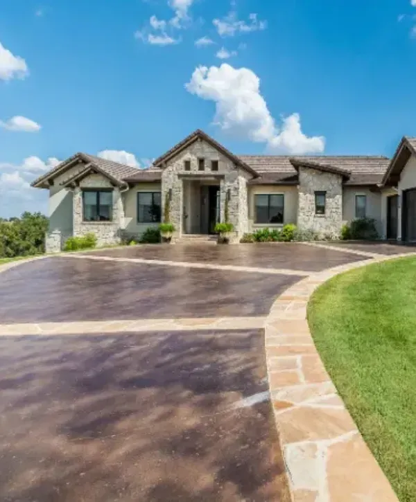 Luxury stone house with a decorative stained concrete driveway and stone border