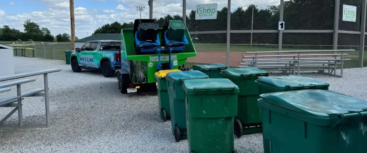 Commercial trash bin cleaning service with multiple green bins lined up for washing.