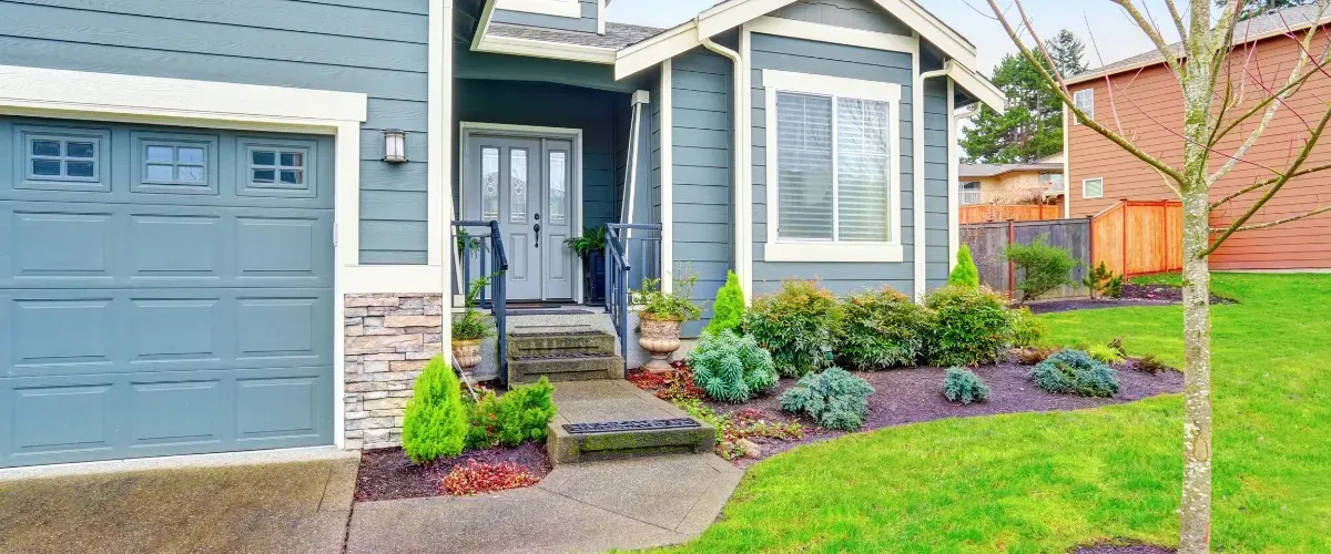 Beautifully landscaped front yard and home entryway with manicured shrubs and a welcoming pathway.