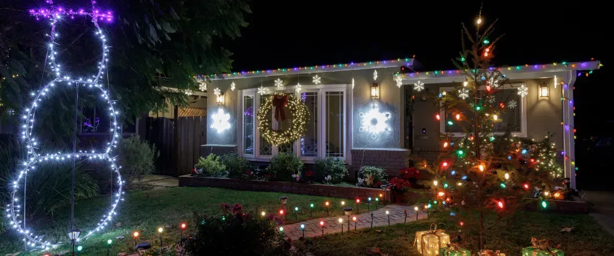 Home exterior fully decorated with colorful Christmas lights, wreath, and festive yard display.