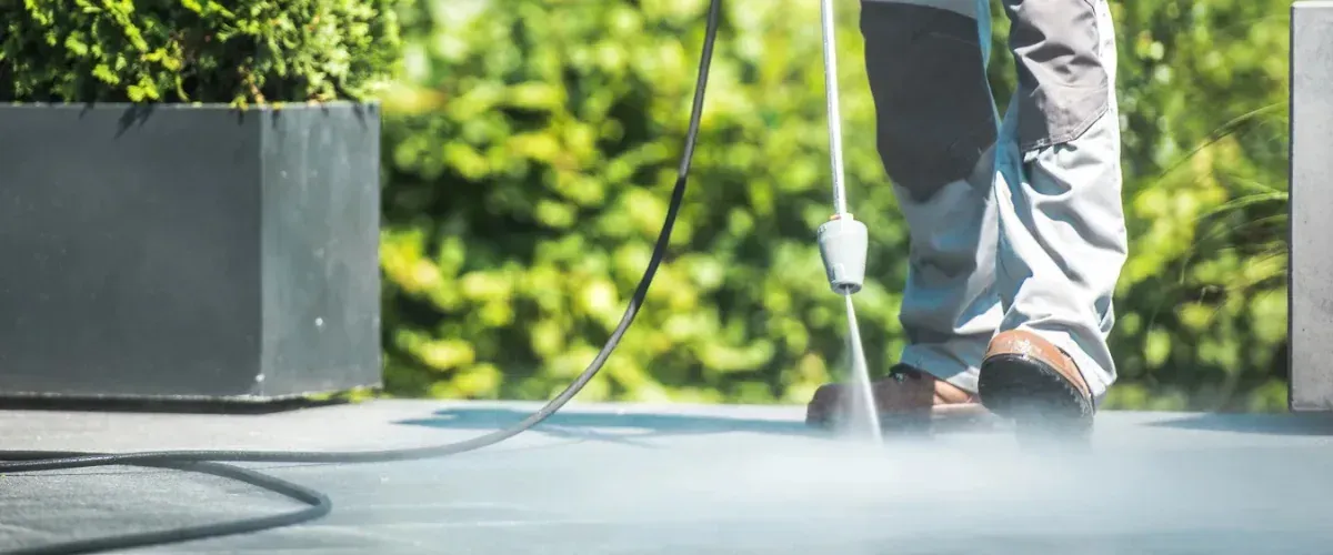 Close-up view of pressure washing an outdoor hard surface with high-pressure water.