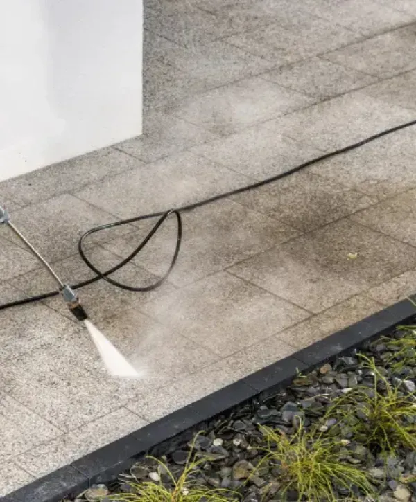 Power washing outdoor tile walkway next to building