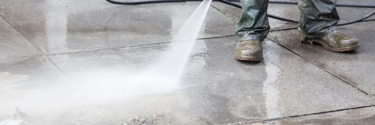 Pressure washer cleaning dirty patio tiles with visible clean path.