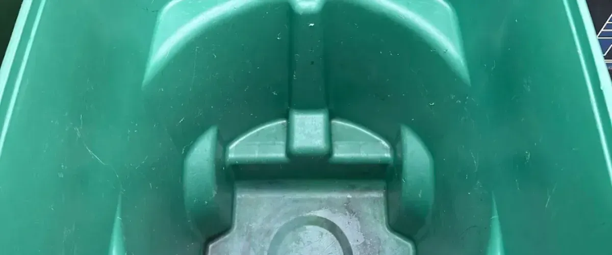 A close-up, high-angle view of the textured, molded interior of a green plastic boat or kayak, showing slight wear.