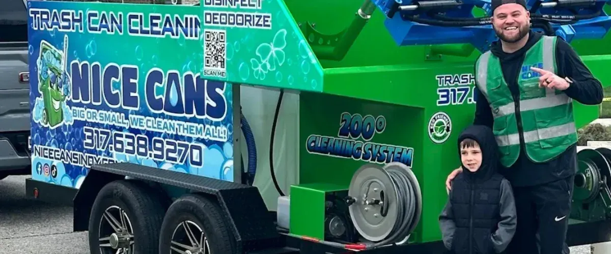 A close-up of a green sanitizing machine with blue hydraulic arms emitting a fine mist, parked on a sunny day.
