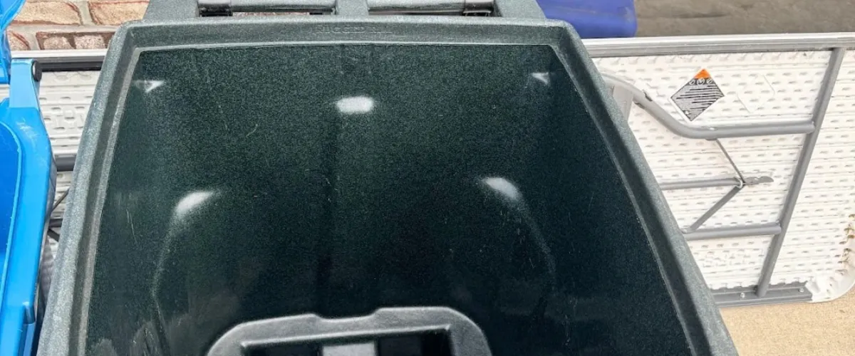 A top-down view inside a textured dark grey utility cart with light reflections on its plastic surface.