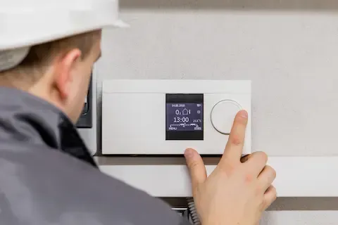 HVAC technician setting digital thermostat for Woodburn HVAC